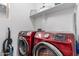 Modern laundry room with red Samsung washer and dryer, plus storage at 2067 N Marketside Ave, Buckeye, AZ 85396