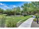 Scenic view of the community grounds featuring a well-manicured lawn, mature trees, and a winding sidewalk on a bright, sunny day at 2425 W Bronco Butte Trl # 2008, Phoenix, AZ 85085
