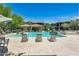 Community pool surrounded by lounge chairs, landscaping, and residential buildings under clear sky at 2425 W Bronco Butte Trl # 2008, Phoenix, AZ 85085