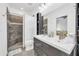 Bright bathroom features a double sink vanity and a walk-in shower with gray and white tiles at 26065 W Yukon Dr, Buckeye, AZ 85396