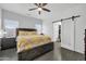 Bright bedroom with a ceiling fan, two windows, and a sliding barn door to an ensuite bathroom at 26065 W Yukon Dr, Buckeye, AZ 85396