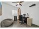 Bright office space with desk, beanbag chair, and modern ceiling fan at 26065 W Yukon Dr, Buckeye, AZ 85396