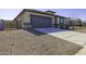 Exterior view of a home with a gray garage door and neutral colored stucco, landscaping, and long driveway at 38197 W San Clemente St, Maricopa, AZ 85138