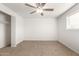 A simple bedroom with carpeted floors, ceiling fan, and large window at 407 E Eason Ave, Buckeye, AZ 85326