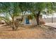 Charming single-story home with a vibrant blue front door surrounded by mature trees at 407 E Eason Ave, Buckeye, AZ 85326