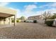 Wide angle of gravel backyard featuring minimal landscaping and a covered patio area at 4429 W Paseo Way, Laveen, AZ 85339