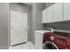 Laundry room with white cabinets, gray walls, tile floors, and red front loading washing machine at 4429 W Paseo Way, Laveen, AZ 85339
