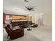 Inviting living room featuring a leather sectional sofa, ceiling fan, and seamless flow into the kitchen at 4429 W Paseo Way, Laveen, AZ 85339