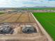 Sweeping aerial shot of a new residential development near expansive green farmland under a blue sky at 7295 S 221St Ave, Buckeye, AZ 85326