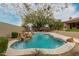 Inviting backyard pool featuring a rock waterfall, basketball hoop, and lush landscaping at 7829 E Softwind Dr, Scottsdale, AZ 85255