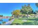 Scenic park view with lake, bench, green grass, and mature trees under a clear blue sky at 10762 W Cimarron Dr, Peoria, AZ 85373