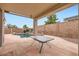 Covered patio beside backyard pool with a rock waterfall feature and an outdoor table for entertaining at 10762 W Cimarron Dr, Peoria, AZ 85373