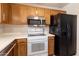 Kitchen view showcasing oak cabinets, white appliances including a microwave, range, and a refrigerator at 10815 N 117Th Pl, Scottsdale, AZ 85259