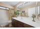 Neutral bathroom featuring a bath tub, dark brown vanity, and a large mirror, providing an inviting, well-lit space at 12926 W Pershing St, El Mirage, AZ 85335