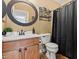 A well-lit bathroom features a vanity, toilet, round mirror, and dark shower curtain at 12947 W Mauna Loa Ln, El Mirage, AZ 85335