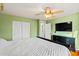 A bright bedroom with a ceiling fan, closet, and a view of an ensuite bathroom at 12947 W Mauna Loa Ln, El Mirage, AZ 85335