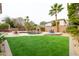 Beautiful backyard featuring a pool, palm trees, artificial grass, and stone details at 15146 W Highland Ave, Goodyear, AZ 85395