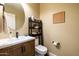 Powder room featuring a wooden vanity, stylish round mirror and a modern toilet at 15146 W Highland Ave, Goodyear, AZ 85395