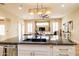 Modern kitchen island with black countertop, white cabinets, and woven pendant lights overlooking the living area at 15146 W Highland Ave, Goodyear, AZ 85395