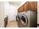 Well-equipped laundry room with wooden cabinets and high-end washer and dryer units at 15146 W Highland Ave, Goodyear, AZ 85395