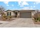 Inviting single-story home with stone veneer, a paved driveway, manicured landscaping, and an attached two-car garage at 16278 W Jenan Dr, Surprise, AZ 85379