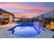 A luxurious pool reflecting the sunset sky features a lovely waterfall feature and ample patio space at 16278 W Jenan Dr, Surprise, AZ 85379