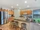 Well-lit kitchen featuring an island, breakfast bar, stainless steel refrigerator, and light wood cabinets at 17542 W Pinnacle Vista Dr, Surprise, AZ 85387