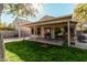 Serene backyard featuring a covered patio, lush lawn, and well-maintained landscaping at 17634 W Hearn Rd, Surprise, AZ 85388