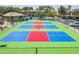 Aerial view of pickleball courts featuring bright blue and red surfaces with surrounding green space and nearby buildings at 1825 W Ray Rd # 2116, Chandler, AZ 85224