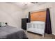 Cozy bedroom with a dark dresser, neutral walls, and a white baby crib near a window at 19075 E Pelican Dr, Queen Creek, AZ 85142