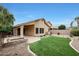 Backyard view featuring a covered patio, artificial turf, desert plants, and a brick perimeter fence at 2416 E Cielo Grande Ave, Phoenix, AZ 85024