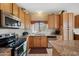 Well-lit kitchen featuring wooden cabinets, granite countertops, and modern stainless steel appliances at 2568 N Armour Ave, Mesa, AZ 85215