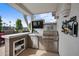 Outdoor kitchen with stainless steel appliances, built-in grill, mini fridge, bar and a television for entertaining guests at 2568 N Armour Ave, Mesa, AZ 85215