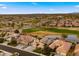 Aerial view of a neighborhood with houses, golf course, water feature, and mountain views at 3400 E Isaiah Ave, Gilbert, AZ 85298