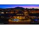 Aerial view of a home with a backyard featuring a pool, green lawn, and landscape lighting at dusk at 3400 E Isaiah Ave, Gilbert, AZ 85298