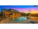 A luxurious backyard pool is illuminated by the sunset, featuring a spa and outdoor seating areas for relaxation and entertainment at 3400 E Isaiah Ave, Gilbert, AZ 85298