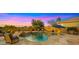 Resort-style backyard oasis with a sparkling pool, hot tub, waterfall feature, and ample seating under shaded umbrellas at 3400 E Isaiah Ave, Gilbert, AZ 85298