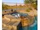 Inviting backyard spa with a waterfall feature, overlooking a tranquil lake and beautiful landscaping at 3400 E Isaiah Ave, Gilbert, AZ 85298