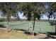 Outdoor tennis courts enclosed by fencing, set in a lush green space with mature trees and manicured landscaping at 3400 E Isaiah Ave, Gilbert, AZ 85298