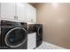 Well-equipped laundry room with dark front load washer/dryer, cabinetry and basin sink at 34801 N 53Rd St # 2, Cave Creek, AZ 85331