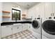 Clean laundry room featuring white cabinets, black countertops, a farmhouse sink, and modern appliances at 3538 E Glenrosa Ave, Phoenix, AZ 85018