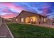 Covered backyard patio with seating, green grass, rock border, and a vibrant sunset at 3768 S Coach House Dr, Gilbert, AZ 85297