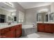 A main bathroom with dual sinks, wood cabinetry, a large bathtub, and modern fixtures at 3768 S Coach House Dr, Gilbert, AZ 85297