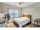 This bedroom features a ceiling fan, tan walls, a window, and a bed with a padded headboard at 4473 E Whitehall Dr, San Tan Valley, AZ 85140