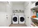 Functional laundry room with washer, dryer, shelving, and storage space at 4473 E Whitehall Dr, San Tan Valley, AZ 85140