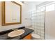 Bathroom featuring black countertop vanity, gold trimmed mirror, toilet, and glass block shower at 4552 E Chuckwalla Cyn, Phoenix, AZ 85044