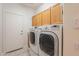 Well-lit laundry room featuring modern washer and dryer set, wooden cabinets, and tiled floor at 4552 E Chuckwalla Cyn, Phoenix, AZ 85044