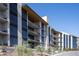 Contemporary multi-story building featuring sleek lines, large windows, and private balconies with desert landscaping at 5000 N Camelback Ridge Rd # 210, Scottsdale, AZ 85251