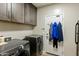 Laundry room with gray cabinetry, modern washer and dryer, and convenient access to the backyard at 5210 E Danbury Rd, Scottsdale, AZ 85254