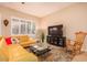 Inviting living room with a plush yellow sectional, stylish rug, and plantation shutters at 6159 W Sequoia Dr, Glendale, AZ 85308